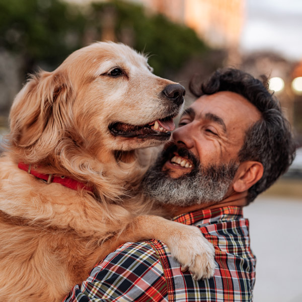 mature man hugging dog outside